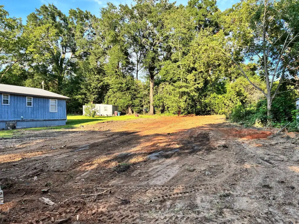 Bare, graded lot after a house teardown, with the neighbor’s blue house beside it