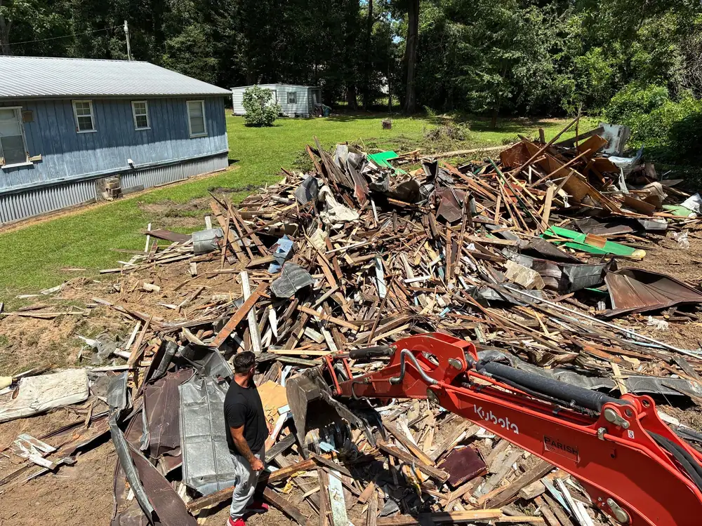 Demolition debris piled for haul-off beside a Kubota excavator arm