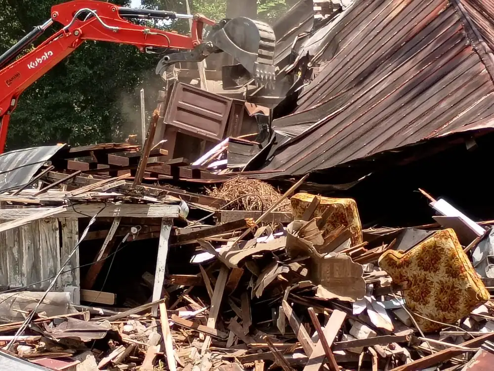 Excavator grabbing debris from a collapsed house